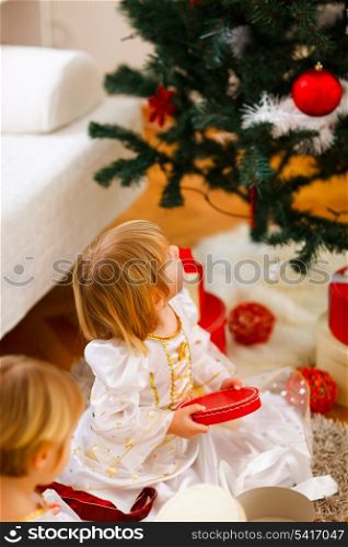 Two girls opening presents near Christmas tree