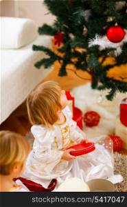 Two girls opening presents near Christmas tree