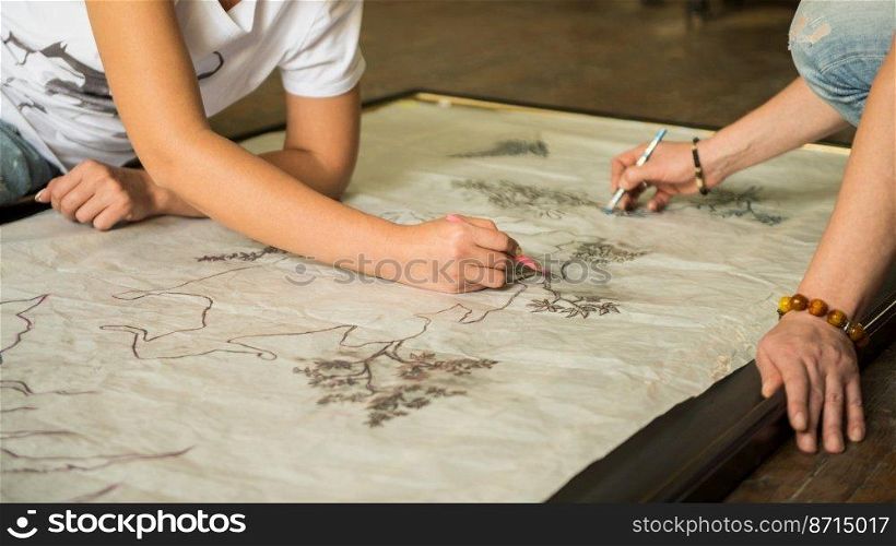 two girls painters draw a sketch through tracing paper, close-up. artist decorator at work