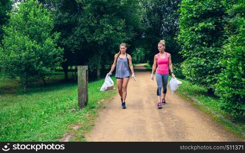 Two girls picking up trash while plogging outdoors. Two girls doing plogging