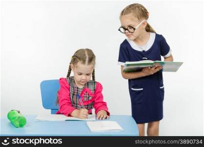 Two girls play school teacher and student. Girl student teacher dictating dictation