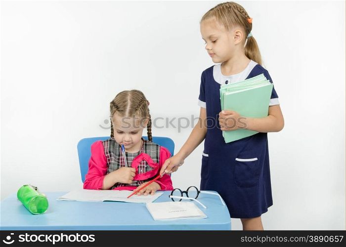 Two girls play school teacher and student. Girl teacher found a mistake in the student notebooks