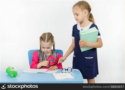 Two girls play school teacher and student. Girl teacher found a mistake in the student notebooks