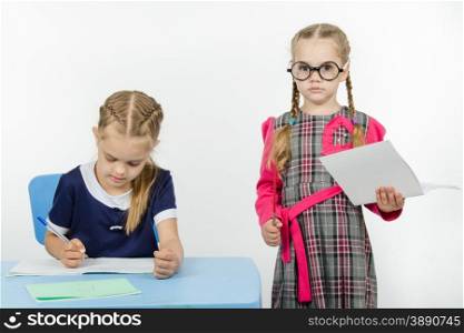 Two girls play school teacher and student. Severe teacher standing at the student