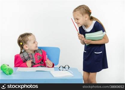 Two girls play school teacher and student. Teacher and student happily smile at each other