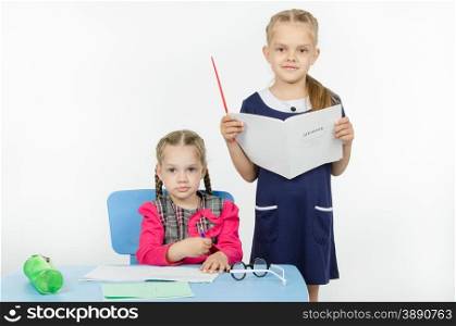 Two girls play school teacher and student. The teacher looks at the student blog