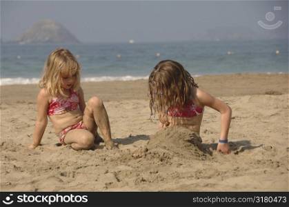 Two girls playing in sand