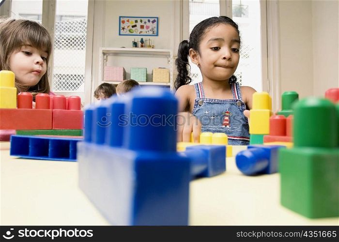 Two girls playing with plastic blocks