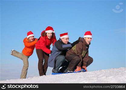 two girls push two men on sled