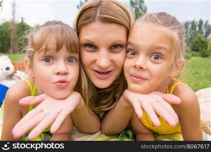 Two girls resting her head on her mother's palm and fun look into the frame