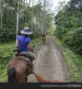 Two girls riding horses on a dirt road, Finca El Cisne, Honduras