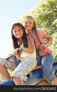 Two Girls Riding On See Saw In Playground