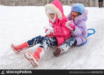 Two girls rolling ice slides. Two girls having fun rolling down the ice slide