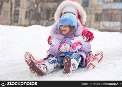 Two girls rolling ice slides. Two girls having fun rolling down the ice slide
