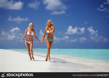 Two girls run along the ocean coast