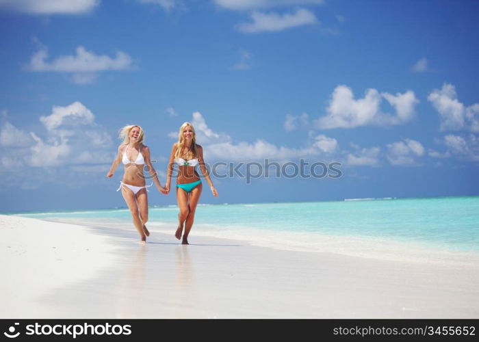 Two girls run along the ocean coast