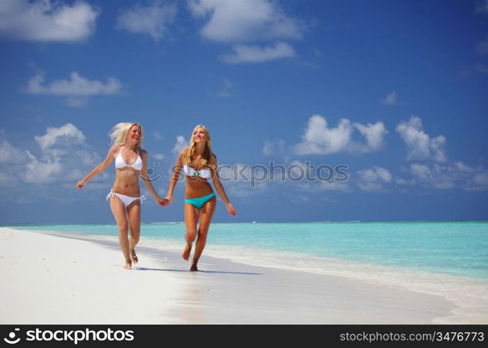 Two girls run along the ocean coast