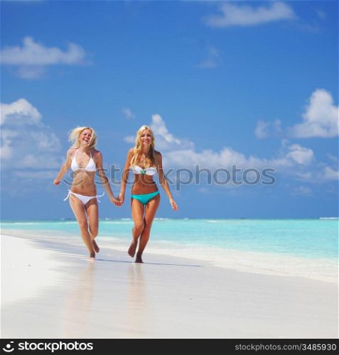Two girls run along the ocean coast