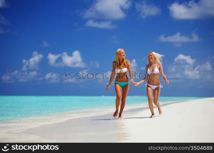 Two girls run along the ocean coast