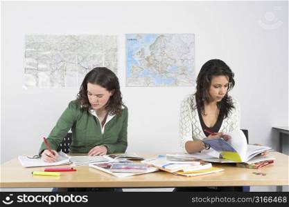 Two girls sitting at a desk at school working hard