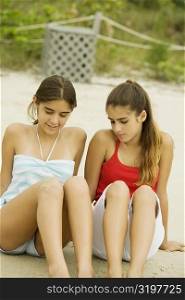 Two girls sitting in sand at the beach
