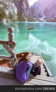 two girls sitting on a pier on the Braies lake, Dolomites Italy