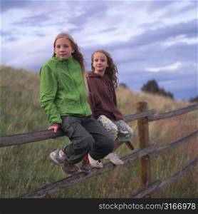 Two girls sitting on fence