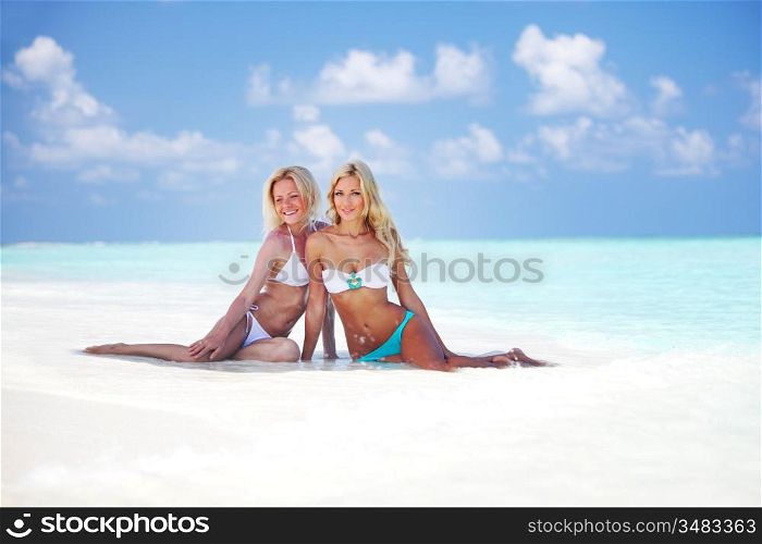 Two girls sitting on the ocean coast