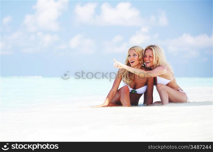 Two girls sitting on the ocean coast