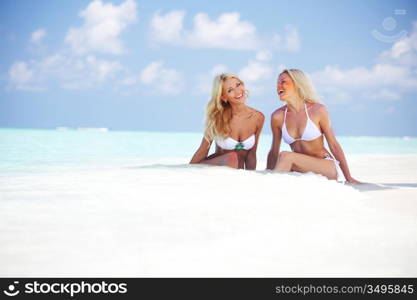 Two girls sitting on the ocean coast