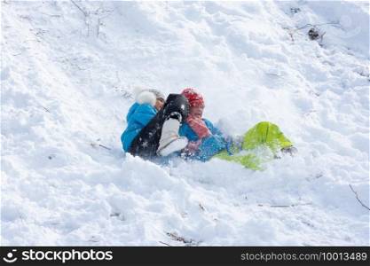 Two girls slide down a slide into a snowdrift