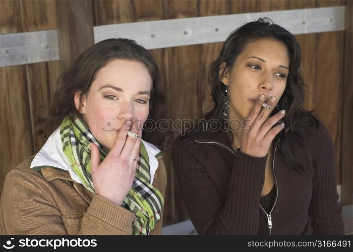 Two girls smoking outside on a cold winter day