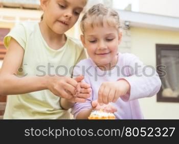 Two girls sprinkle confectionery on Easter cupcakes
