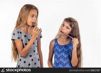 Two girls suck caramel candies