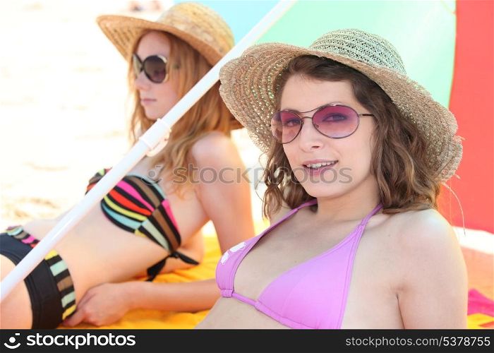 Two girls sunbathing at the beach