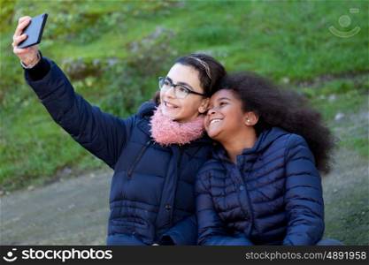 Two girls taking a photo with the mobile in the park.