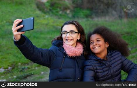 Two girls taking a photo with the mobile in the park.