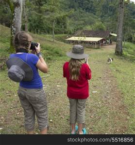 Two girls taking picture with digital cameras in a farm, Finca El Cisne, Honduras
