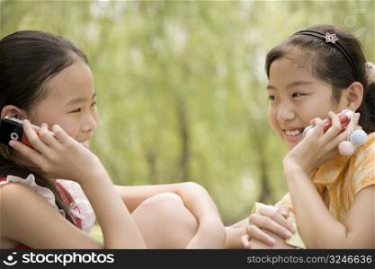 Two girls talking on their mobile phones and smiling