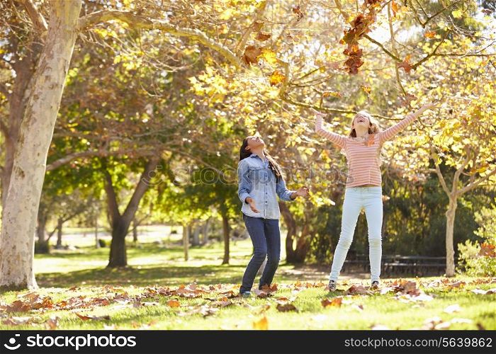 Two Girls Throwing Autumn Leaves In The Air