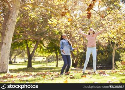 Two Girls Throwing Autumn Leaves In The Air