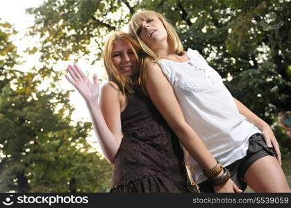two girls together outside in dancing position ready for party with bright sun flares in background