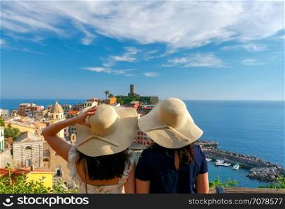 Two girls tourists admiring Vernazza.. Two girls tourists admiring Vernazza. Cinque Terre National Park. Liguria. Italy.