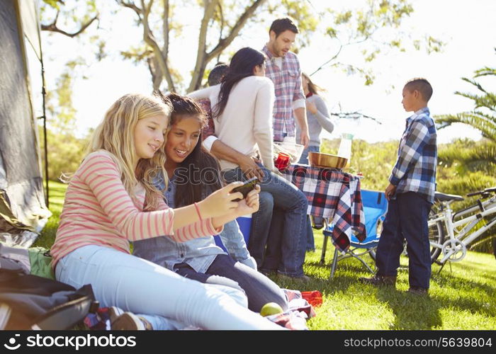 Two Girls Using Mobile Phone On Family Camping Holiday