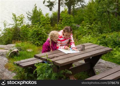 two girls view the map of sitting over wooden table, Norway