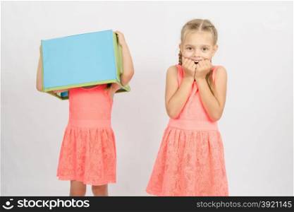 Two girls wearing a box on his head, isolated on a light background