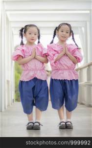 Two girls wearing Thai clothes stand to say hello
