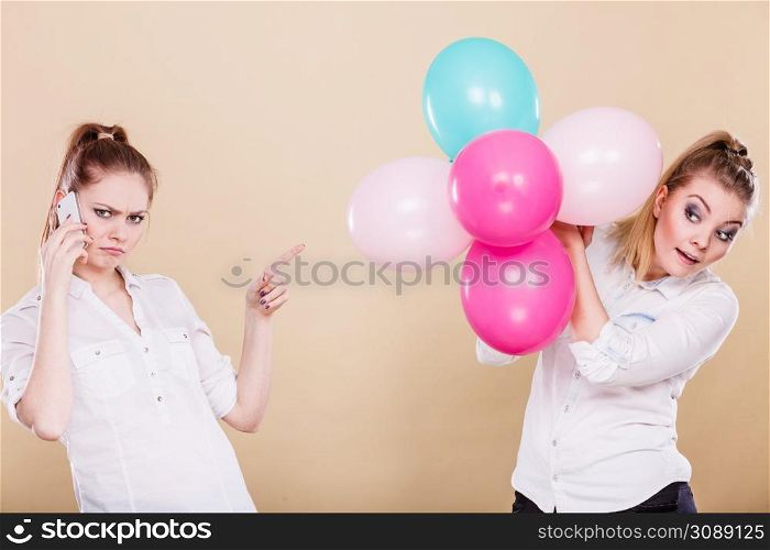 Two girls with colorful balloons and mobile phone. Best friends preparing party celebration, having problem, bad relationship. Two girls with mobile phone and balloons