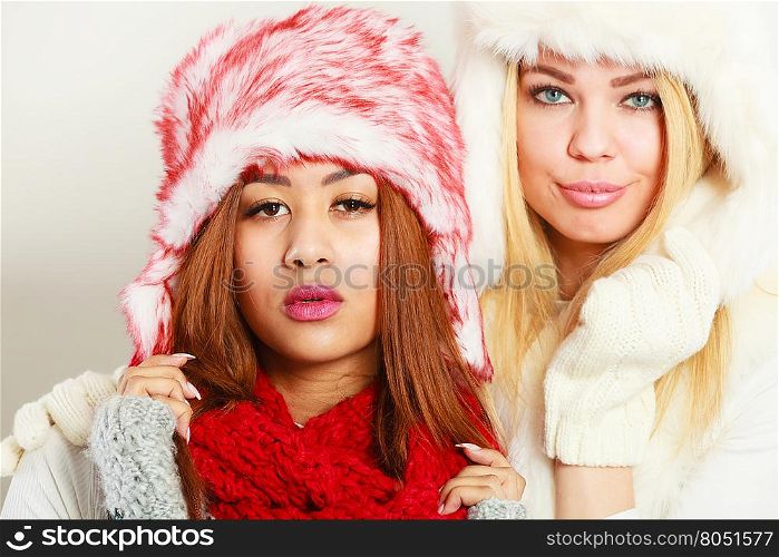 Two girls with winter outfit.. Fashion winter people concept. Two girls with winter outfit. Attractive women wearing fur caps.