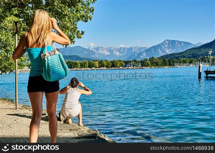 Two Girls woman shoot photos of mountains at lake Worthersee Klagenfurt. Two girls at Worthersee in Klagenfurt